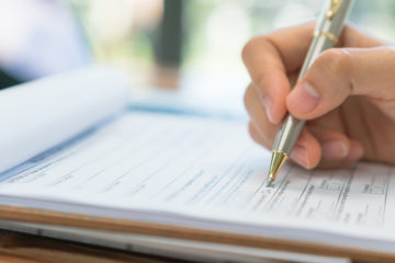 Closeup of a hand holding a pen checking a box on a medical form.